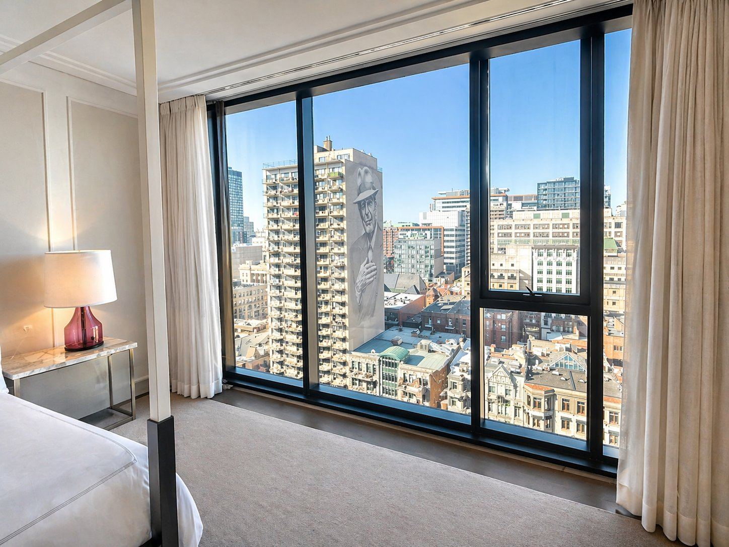 A room at Four Seasons Hotel Montreal with a floor-to-ceiling view of the Leonard Cohen "Tower of Songs" mural above the Golden Square Mile