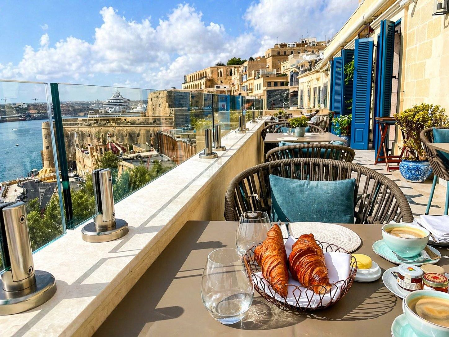 The terrace at Iniala Harbour House Valletta, looking across the Grand Harbour toward Fort St. Angelo and the Three Cities with a cruise ship in port